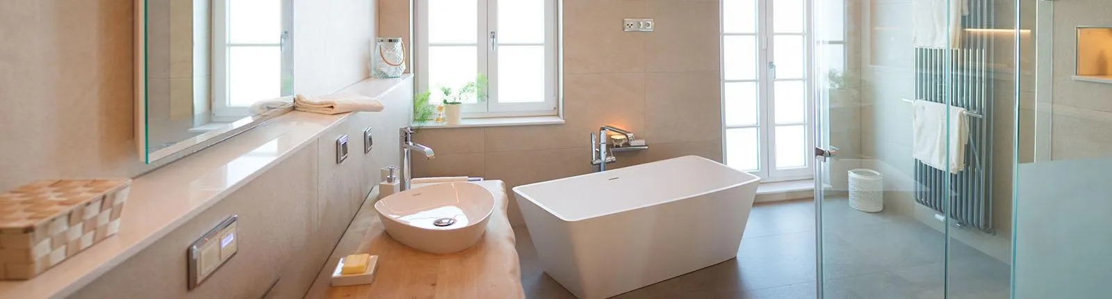 Helles, modernes Badezimmer mit großer begehbarer Dusche, Wandspiegel, weißem Waschtisch und drei Fenstern, die natürliches Licht hereinlassen.