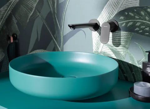 Modernes Badezimmer mit türkisem Waschbecken und Wandtapete mit Blattmotiven. Minimalistisches Design und stilvolle Einrichtung.