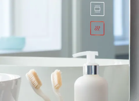 Nahaufnahme eines Badezimmerspiegels mit zwei Touch-Bedienfeldern für Licht und Heizung, das untere Symbol ist rot hervorgehoben. 
