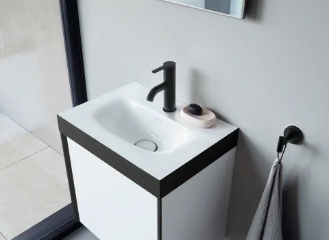 Kleines Badezimmer mit einem schlichten weißen Waschtisch und schwarzer Armatur.