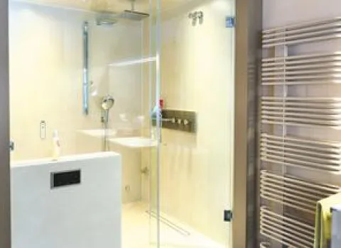 Helle, moderne Dusche mit Glasabtrennung, Regendusche, digitaler Steuerung und stylischem Designheizkörper in Beige-Tönen.