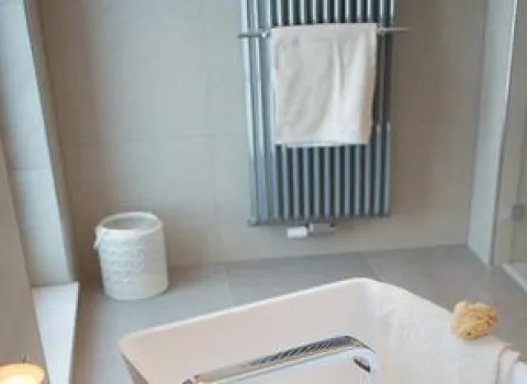 Ausschnitt eines modernen Badezimmers mit freistehender Badewanne im Vordergrund.