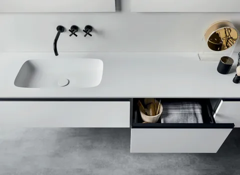 Minimalistisches Bad von Stocco mit weißem Waschtisch, schwarzen Wandarmaturen und geöffnetem Schubfach.