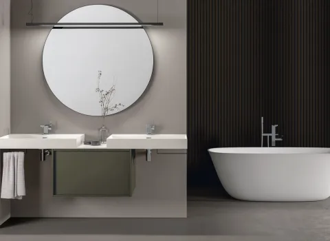 Zeitloses Badezimmer von Stocco mit Doppelwaschtisch, rundem Spiegel, grüner Mittelkonsole und freistehender Badewanne.