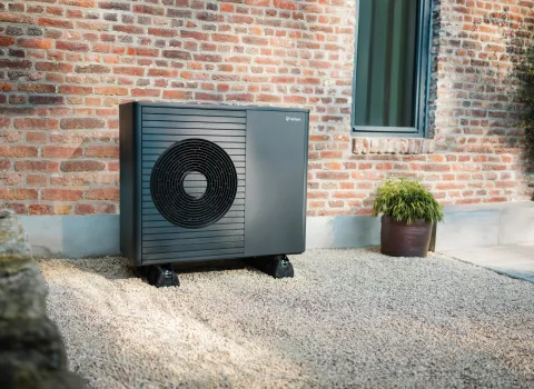 Eine moderne Vaillant-Wärmepumpe steht vor einem Backstein-Altbau.
