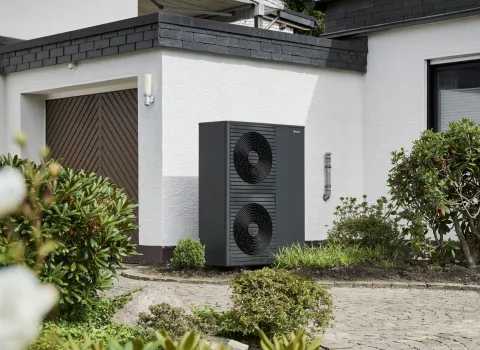 Eine Vaillant Wärmepumpe steht vor einer Garage.