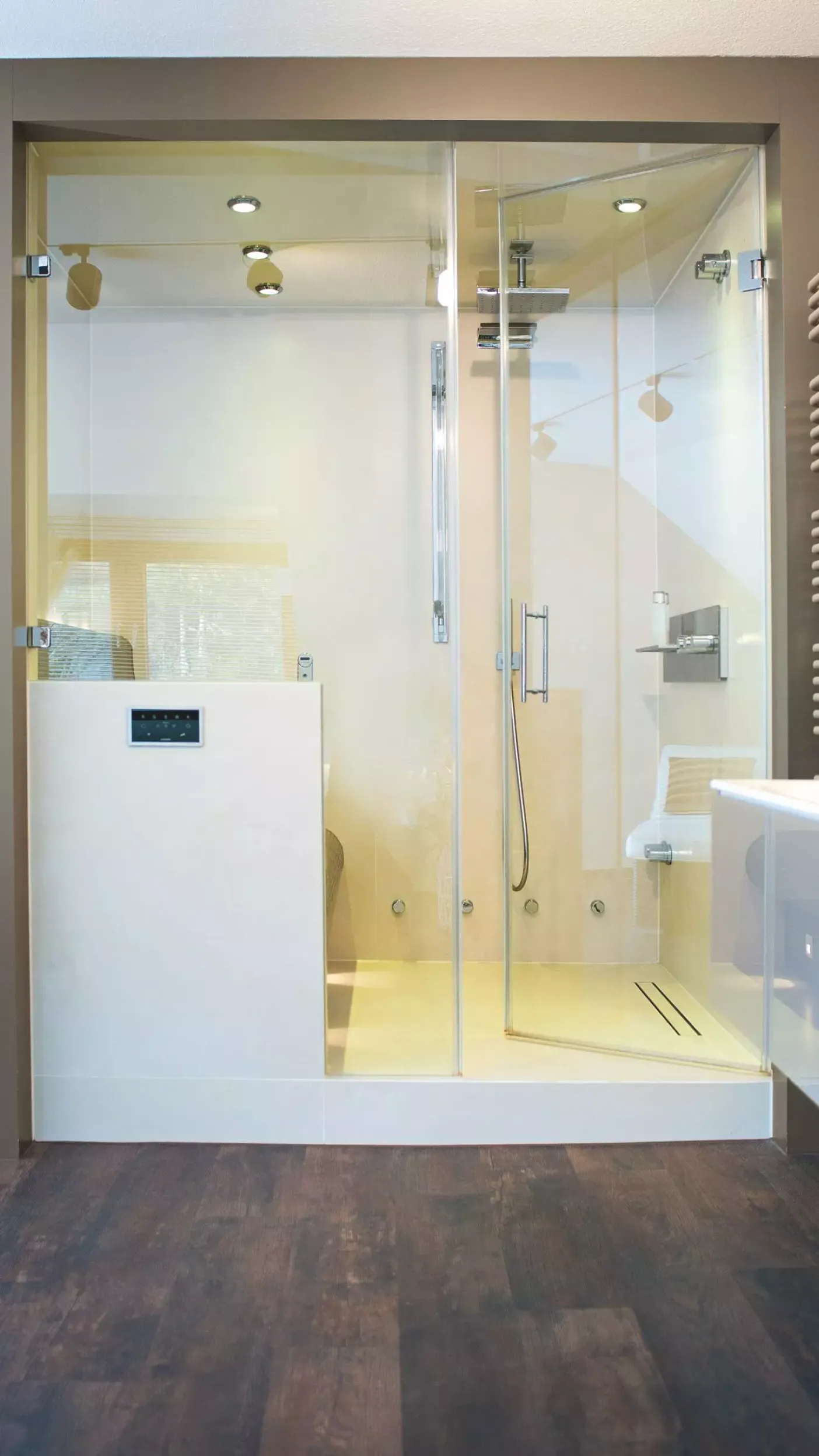 Großzügige begehbare Dusche mit Glaswänden, Regendusche, integrierter Beleuchtung und digitaler Steuerung, daneben moderner Handtuchheizkörper.