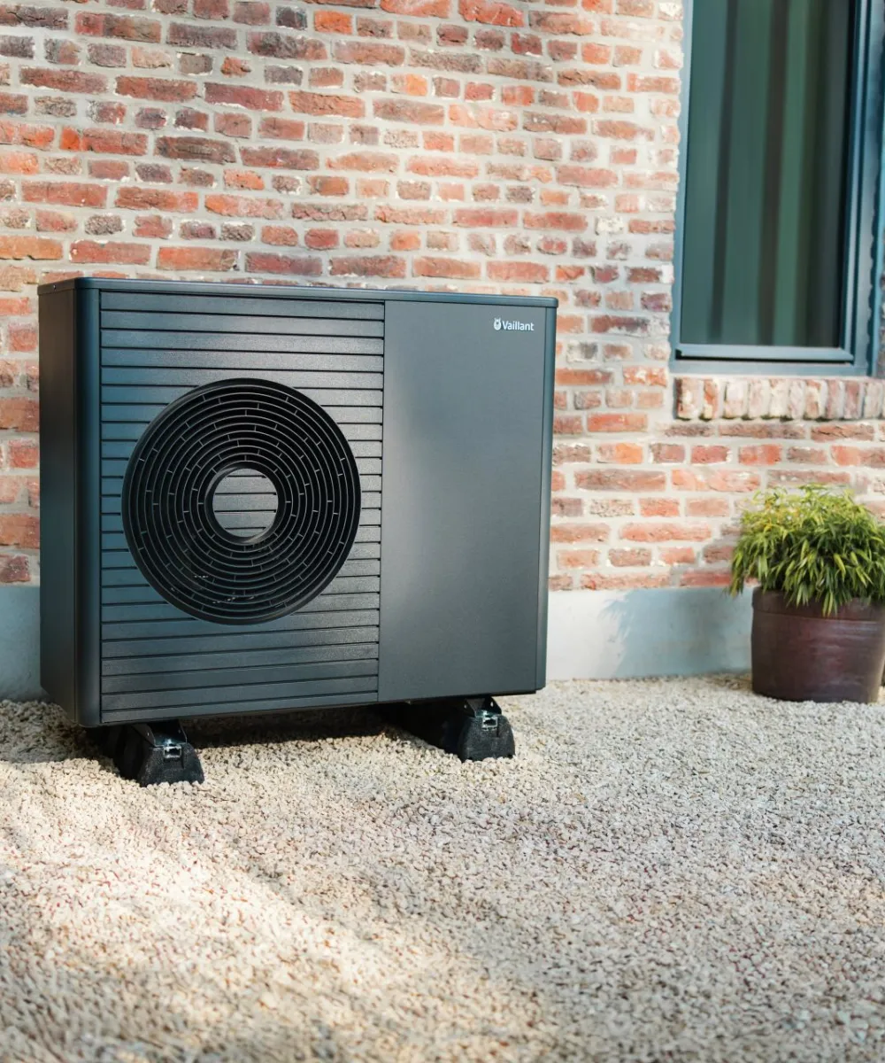 Eine moderne Vaillant-Wärmepumpe steht vor einem Backstein-Altbau.