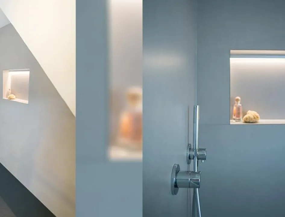 Bodenebene Dusche mit heller Wandverkleidung, dunklem Duschboden, Regendusche und beleuchteter Wandnische für Duschutensilien.